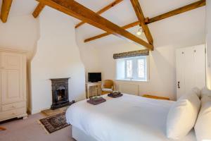 - une chambre avec un lit blanc et une cheminée dans l'établissement Southwaite Cottage, à Outhgill