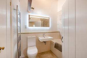 une salle de bains avec toilettes, lavabo et miroir dans l'établissement Southwaite Cottage, à Outhgill 16 autres photos