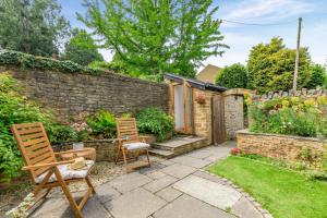 a garden with two chairs and a stone wall at Bonnings Cottage in Barrington
