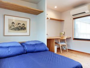 - une chambre avec un lit bleu et un bureau dans l'établissement Kamogawa Sanpo, à Shimmachidōri