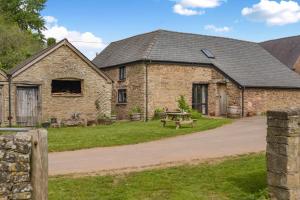 Un edificio de ladrillo con una mesa de picnic delante. en Great Tre-Rhew Farm, en Llanvetherine