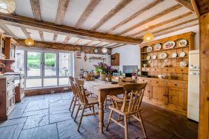 Una cocina con una mesa y sillas de madera. en Great Tre-Rhew Farm, en Llanvetherine