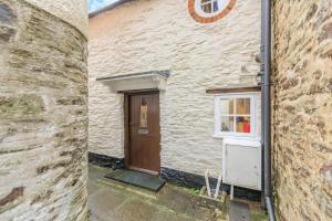 a stone building with a door and a window at Lane Cottage in Dulverton