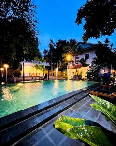 a swimming pool at night with trees and a house at Holy Villa in Kampot +51 photos