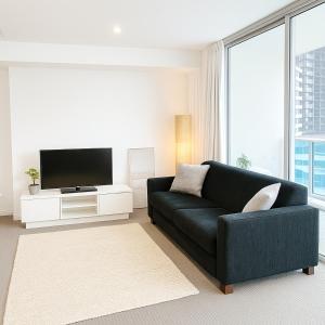 Entire 2 bdrm apt in Hilton Surfers Paradise -7 في غولد كوست: غرفة معيشة مع أريكة سوداء وتلفزيون