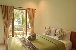 a bedroom with a bed with a teddy bear on it at Maja House Penida in Nusa Penida
