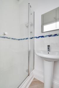 a white bathroom with a sink and a shower at Hannafore Lemain Garden Apts in Looe
