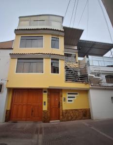 a yellow house with orange doors and a balcony at Apartamento Familiar Tacna Bonita in Tacna