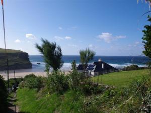 a house on the beach with the ocean in the background at The Buoys in Mawgan Porth