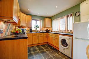 a kitchen with wooden cabinets and a washer and dryer at The Buoys in Mawgan Porth