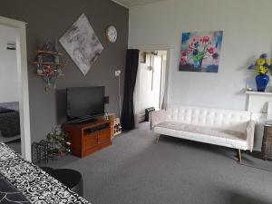a living room with a white couch and a television at Ellie's Villa in Brydone