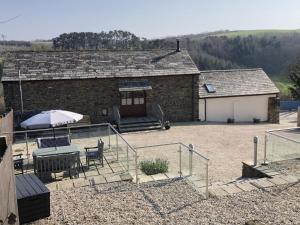 a building with a table and chairs and an umbrella at Woods Close at Sanctuary Farm in Kilkhampton