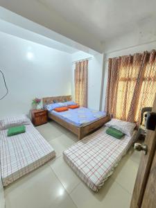 Habitación con 3 camas y cortinas. en Bel's Cozy Suites at Lavernie, en Baguio