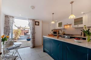 a kitchen with blue cabinets and a large window at Cheriton Coastal Cottage in Deal