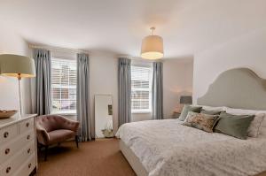 a bedroom with a bed and a chair and windows at Cheriton Coastal Cottage in Deal