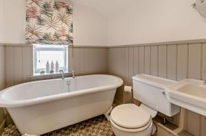 a bathroom with a tub and a toilet and a sink at Cheriton Coastal Cottage in Deal