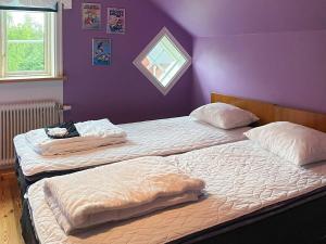 two beds in a bedroom with a purple wall at 8 person holiday home in Virestad in Virestad