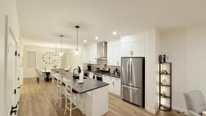 Una cocina con gabinetes blancos y una mesa y un refrigerador. en Casa Koko, en Calgary