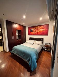 a bedroom with a large bed with a painting on the wall at Apartamento de lujo con sauna a solo 10 minutos del Aeropuerto El Dorado in Bogotá