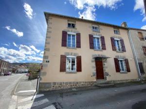 a building with red shuttered windows on a street at Résidence Galia in Sainte-Feyre