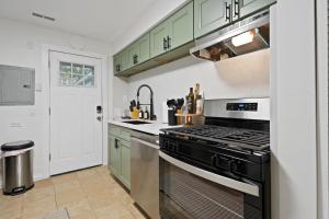 a kitchen with green cabinets and a stove top oven at Stylish Evanston Retreat Near NU & Lakefront in Evanston