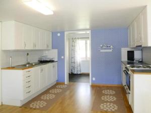 a kitchen with white cabinets and a blue wall at 4 person holiday home in Brålanda in Brålanda +13 photos