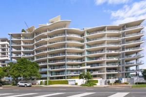 a large apartment building with balconies on a street at Beachside Penthouse w Private Rooftop & Oceanviews in Caloundra