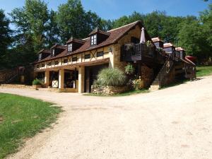 ein großes Haus mit Balkon auf einer unbefestigten Straße in der Unterkunft Le Coustal in Auriac-du-Périgord