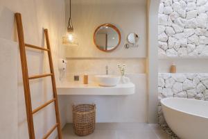 a bathroom with a sink and a tub and a mirror at Ulu Hill Top By Hello Summer in Uluwatu +3 photos