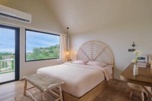 a bedroom with a large bed and a window at Ulu Hill Top By Hello Summer in Uluwatu