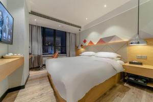a bedroom with a large white bed and a window at Borrman Hotel Puning International Commodity City Wantaihui in Jieyang