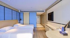a hotel room with two beds and a tv at Echarm Hotel Aegean Shopping Park Zhonghuan Plaza in Fujiatun