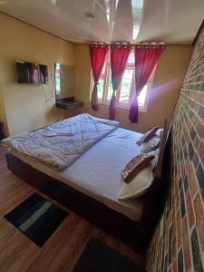 ein großes Bett in einem Schlafzimmer mit roten Vorhängen in der Unterkunft Zambala Garden Resort in Gangtok + 23 Fotos