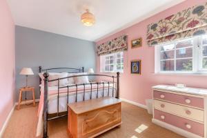 a bedroom with a bed and a dresser and two windows at The Southend Cottage in Ledbury