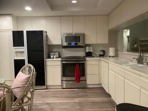 a kitchen with white cabinets and stainless steel appliances at Palm Valley Country Club, Pickleball, Tennis, Gym, Clubhouse, Swimming Pools, Lux, Spac 2 Bdrms Den 2 Ba in Palm Desert
