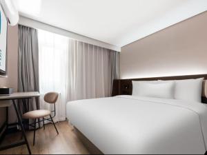 a hotel room with a large white bed and a desk at Hanting Hotel Beijing Fengtai Railway Station Subway Station in Beijing