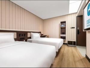a hotel room with two beds and a tv at Hanting Hotel Beijing Fengtai Railway Station Subway Station in Beijing