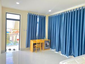 a room with blue curtains and a desk with a television at Hoàng Hôn Nhớ Hotel in Ấp Khánh Phước (1)