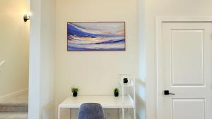 a white desk with a blue chair and a painting on the wall at La Maison de Koko in Calgary