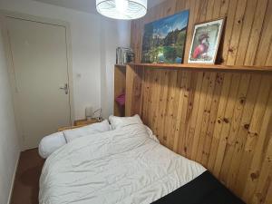ein Schlafzimmer mit einem Bett mit einer Holzwand in der Unterkunft Appartement au pied des pistes à Super Besse - FR-1-814-61 in Besse-et-Saint-Anastaise