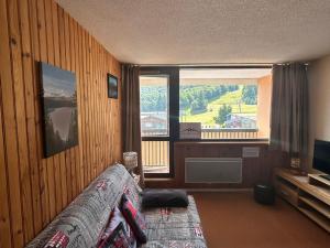 ein Wohnzimmer mit Couch und großem Fenster in der Unterkunft Appartement au pied des pistes à Super Besse - FR-1-814-61 in Besse-et-Saint-Anastaise