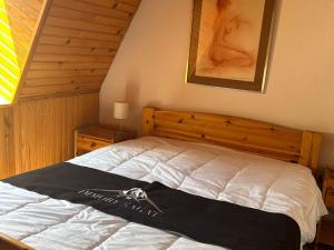 ein Schlafzimmer mit einem weißen Bett mit einem hölzernen Kopfteil in der Unterkunft Appartement spacieux en montagne avec loggia, au cœur de la station, proche piste et lac - FR-1-814-62 in Besse-et-Saint-Anastaise