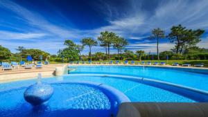 a large swimming pool with blue chairs and trees at NOA Apartment Quinta do Lago in Quinta do Lago