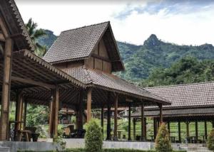 a large wooden pavilion with a mountain in the background at Giri Tengah Resort Borobudur in Ngargoremo +21 photos