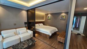 Un dormitorio con una cama y un sofá en una habitación. en Haeundae Elbon The Stay, en Busan