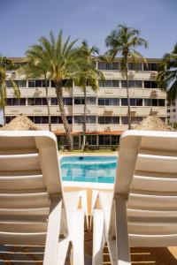 Dos sillas de playa y una piscina frente a un edificio. en Aguamarina Paraiso 2, en Pampatar