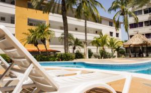 Un par de tumbonas junto a una piscina con un edificio. en Aguamarina Paraiso 2, en Pampatar