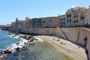 a group of people on a beach near the water at Dammuso di Ponente Ortigia in Siracusa