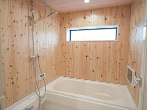 a bathroom with a tub and a window and wooden walls at Kotonoyado Chizu - Vacation STAY 83866v in Kotohira