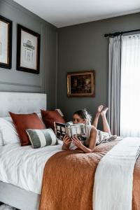 a woman laying on a bed reading a book at Historic Benambra Boutique Accommodation Queenscliff c1883 in Queenscliff